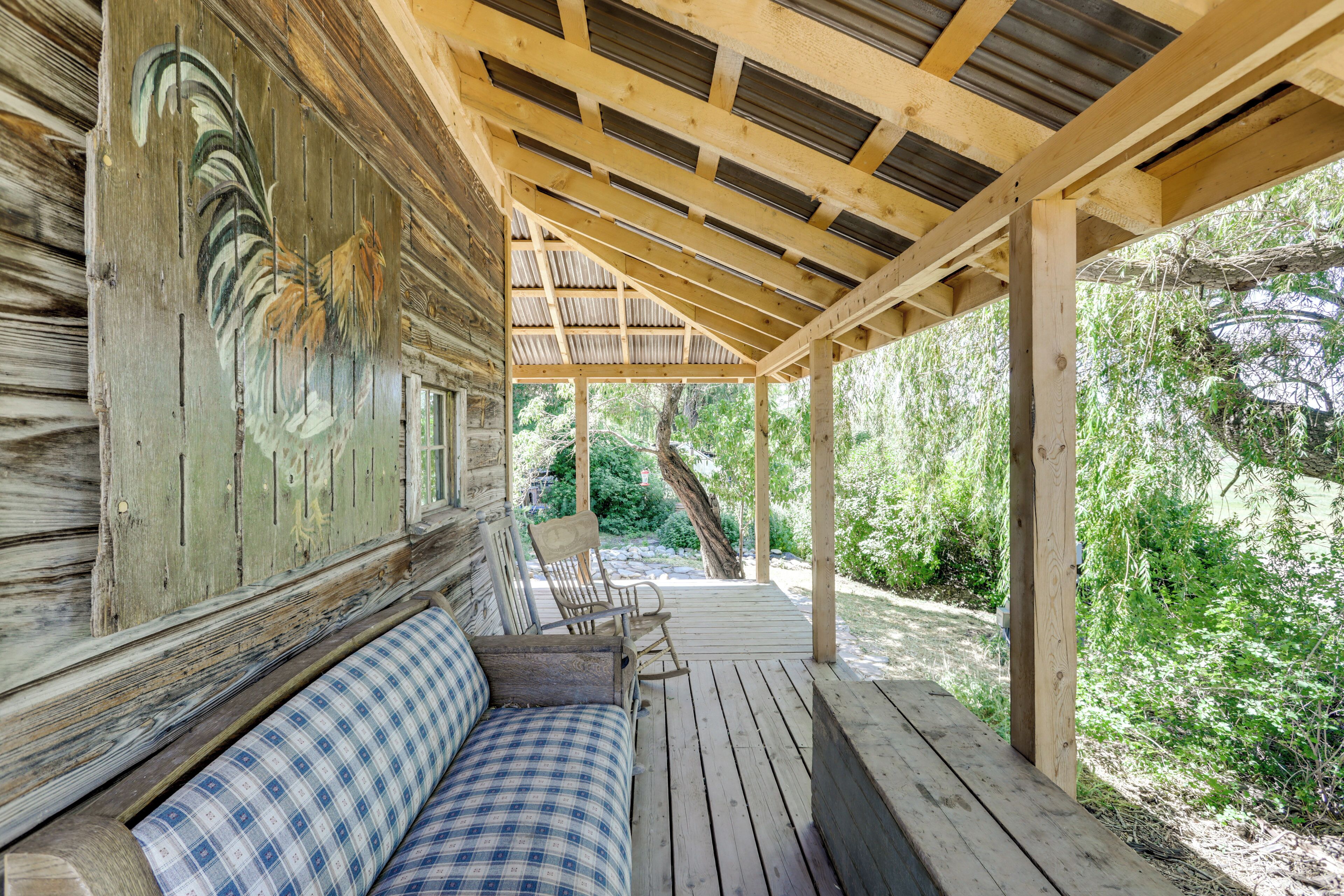A wooden deck with a checkered bench and a rustic wall with a painted rooster.
