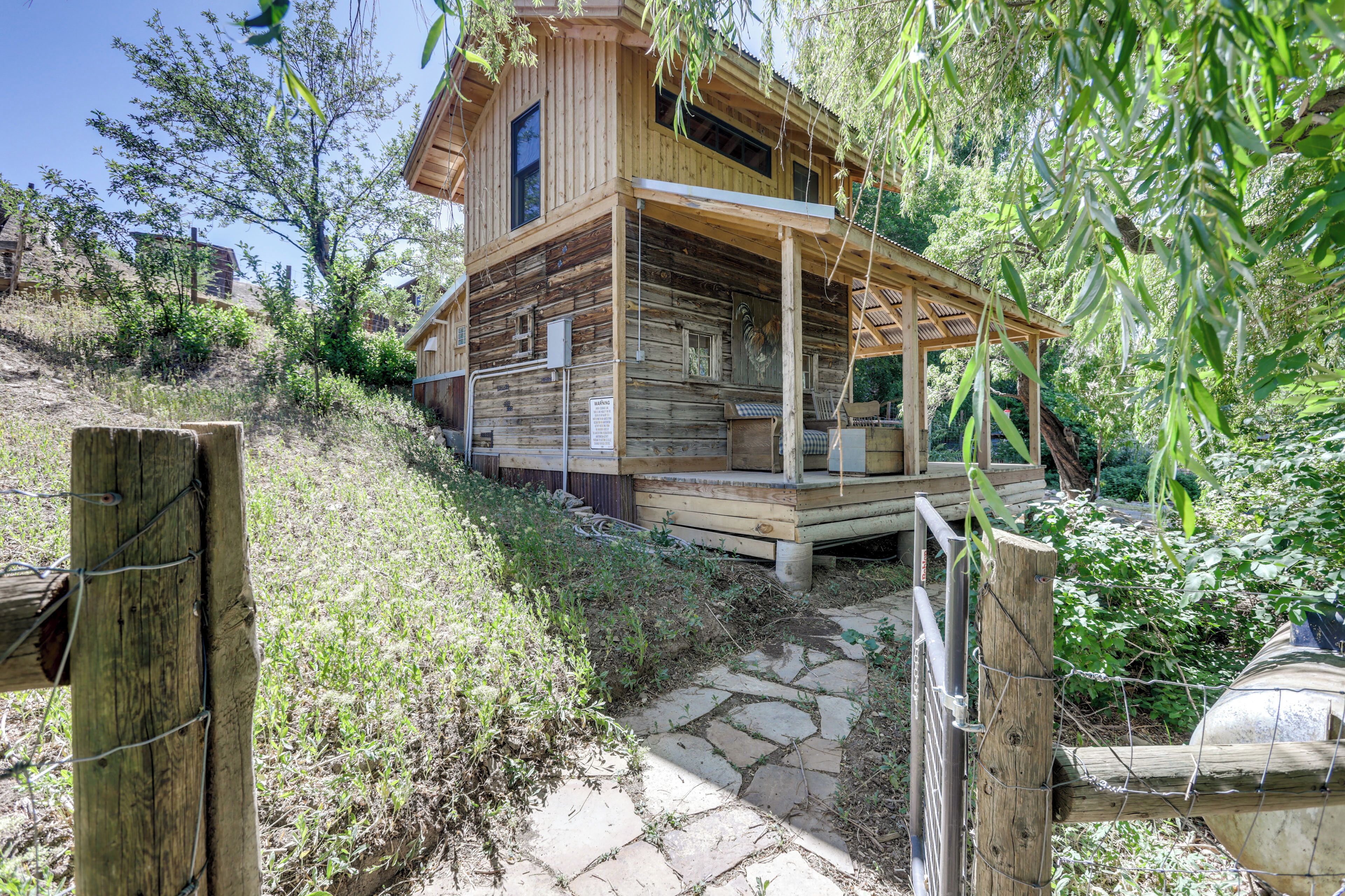 Eine Holzhütte mit Veranda, umgeben von Grün und einem Kiesweg.