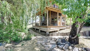 A rustic wooden cabin with a porch, surrounded by trees and a stone pathway. - Historic Nature Lovers Cabin on Farm in Paonia! (Paonia)