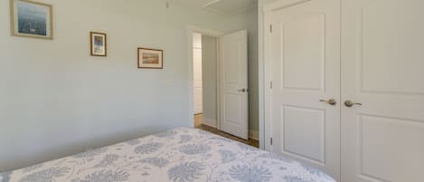 A bedroom with a bed, a ceiling fan, and a door leading to another room.