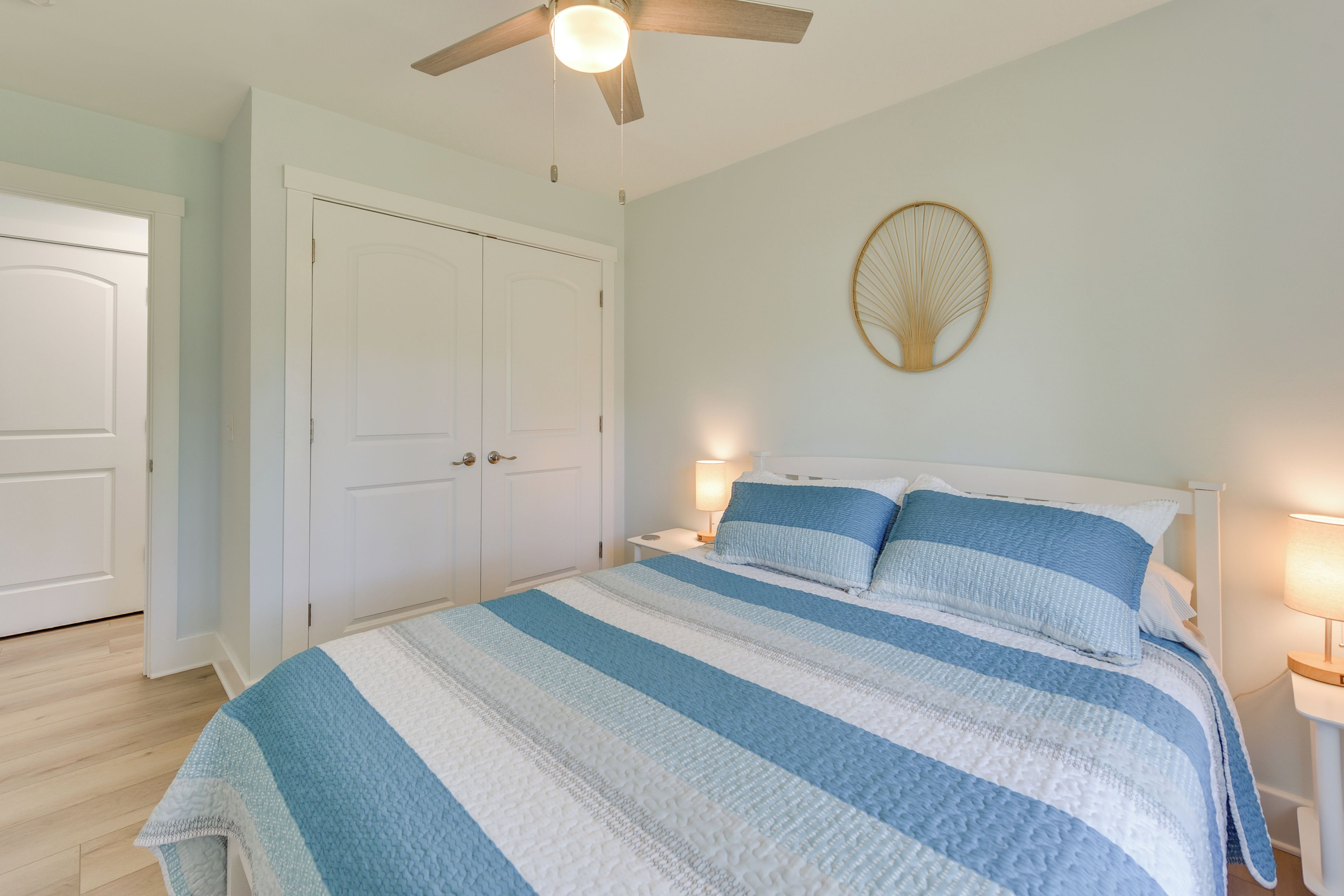 Une chambre à coucher avec un grand lit, une armoire blanche et un ventilateur de plafond.