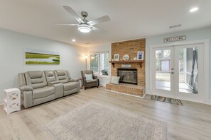 A spacious living room with a beige leather sofa, a fireplace, and a ceiling fan. - 5 Mi to Dtwn Beaufort: Home w/ Screened-in Patio (Port Royal)