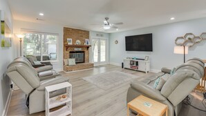A spacious living room with a fireplace, leather sofas, a flat-screen TV, and a ceiling fan. - 5 Mi to Dtwn Beaufort: Home w/ Screened-in Patio (Port Royal)