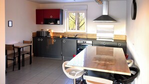 Een moderne keuken met een groot raam, een eettafel en een rode kast.