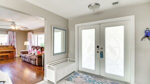 A spacious living room with a piano, a sofa with floral cushions, and a large mirror. - Centrally Located Cocoa Beach Haven: Walk to Shore (Cocoa Beach)