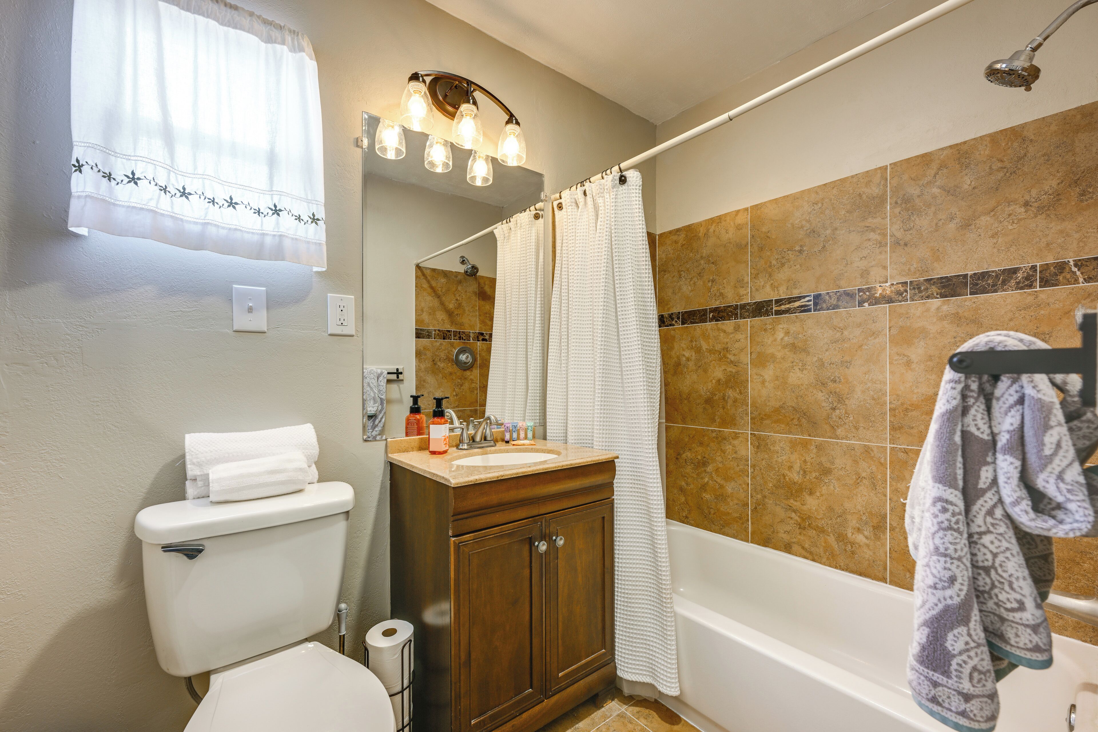 A bathroom with a toilet, sink, cabinet, shower, and a towel rack.