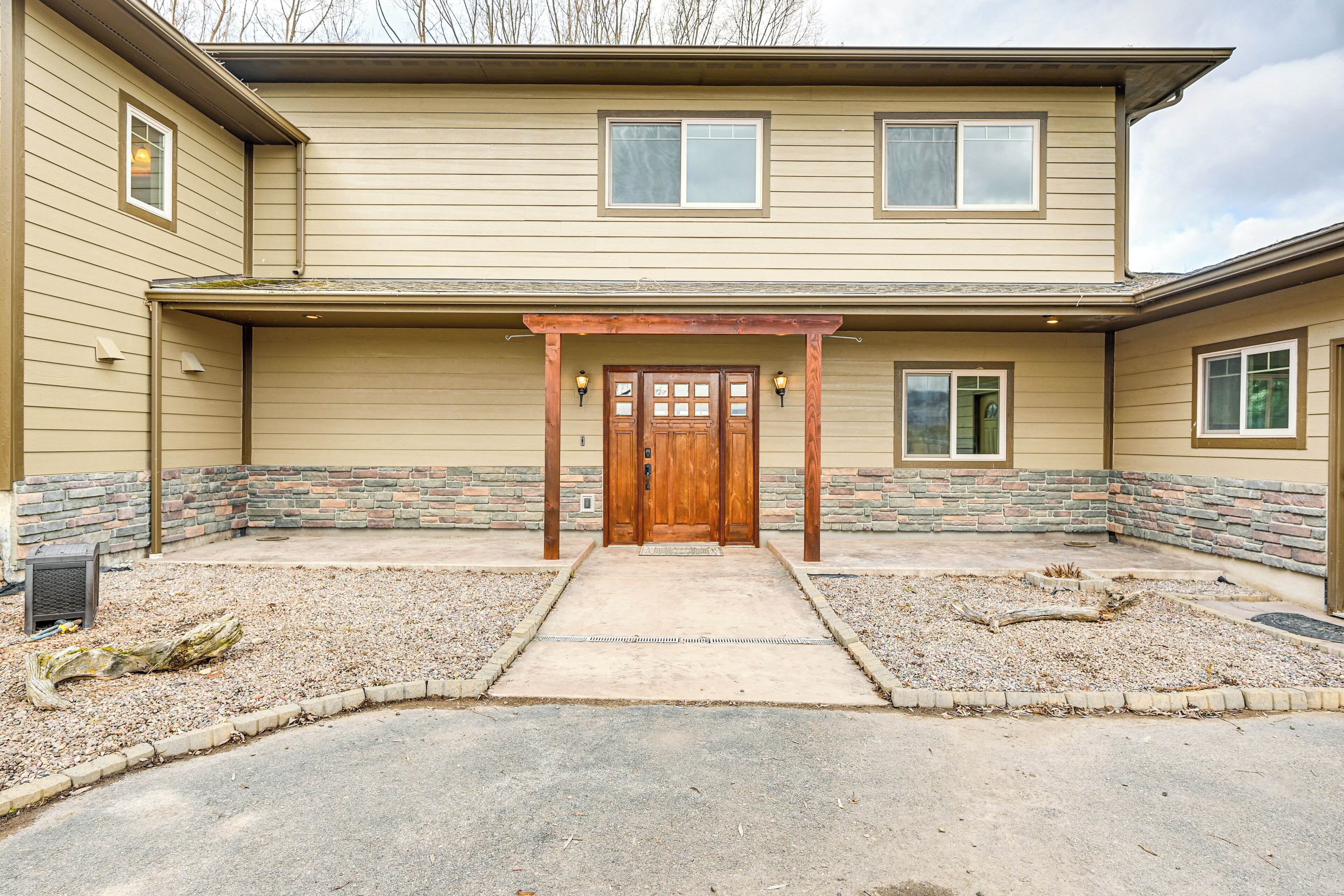 A two-story house with a front porch, a wooden door, and stone accents.