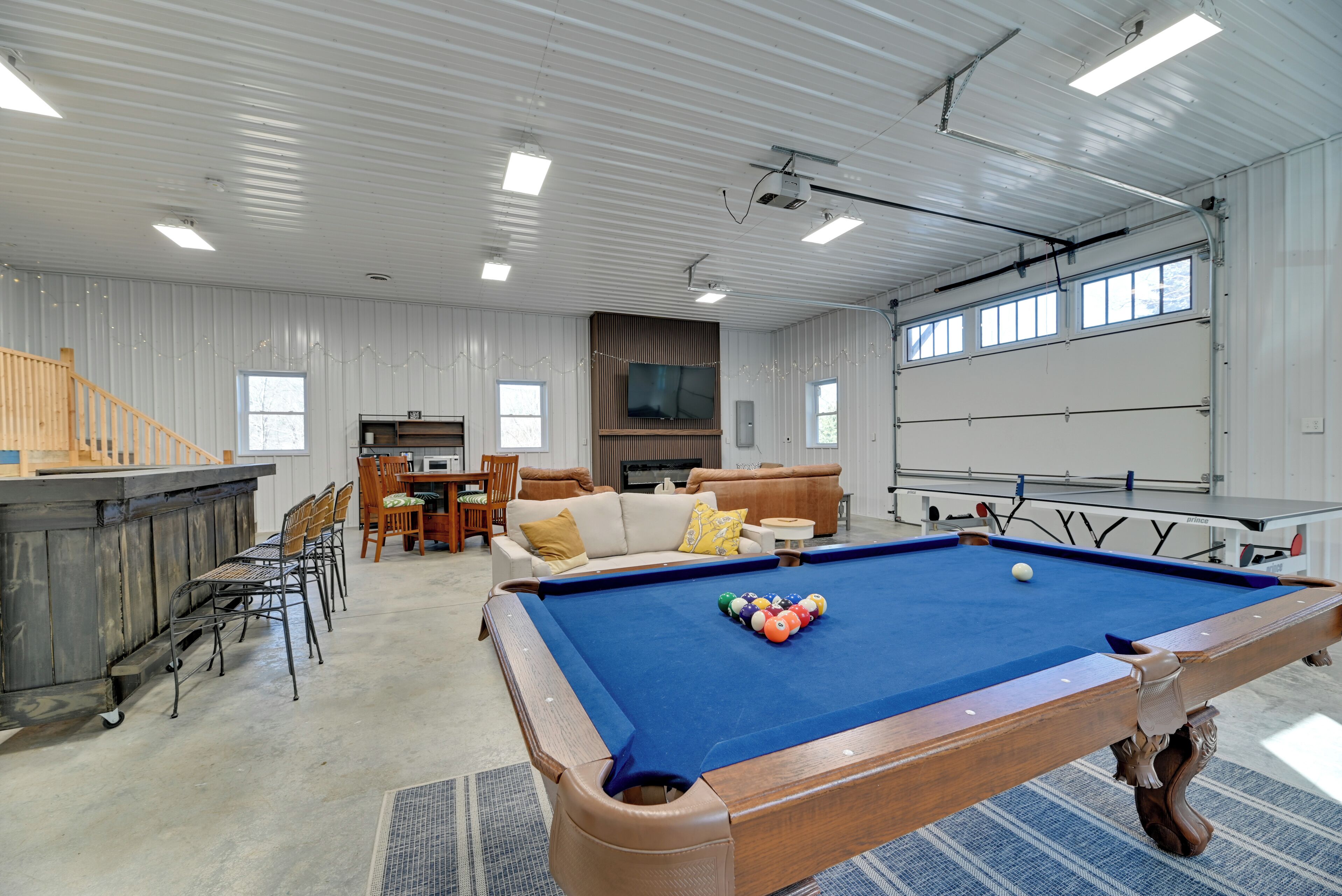 Een pooltafel in een ruimte met een hoge plafond, een bar en een zithoek met een televisie.