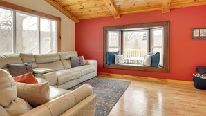 A living room with a large leather sofa, a wooden ceiling, and a red wall. - The Toasted Marshmallow Ski & Lake Game Barn (Canandaigua)