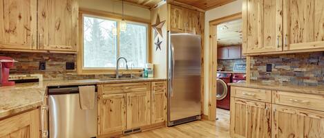 A modern kitchen with wooden cabinets, stainless steel appliances, and a stone backsplash.