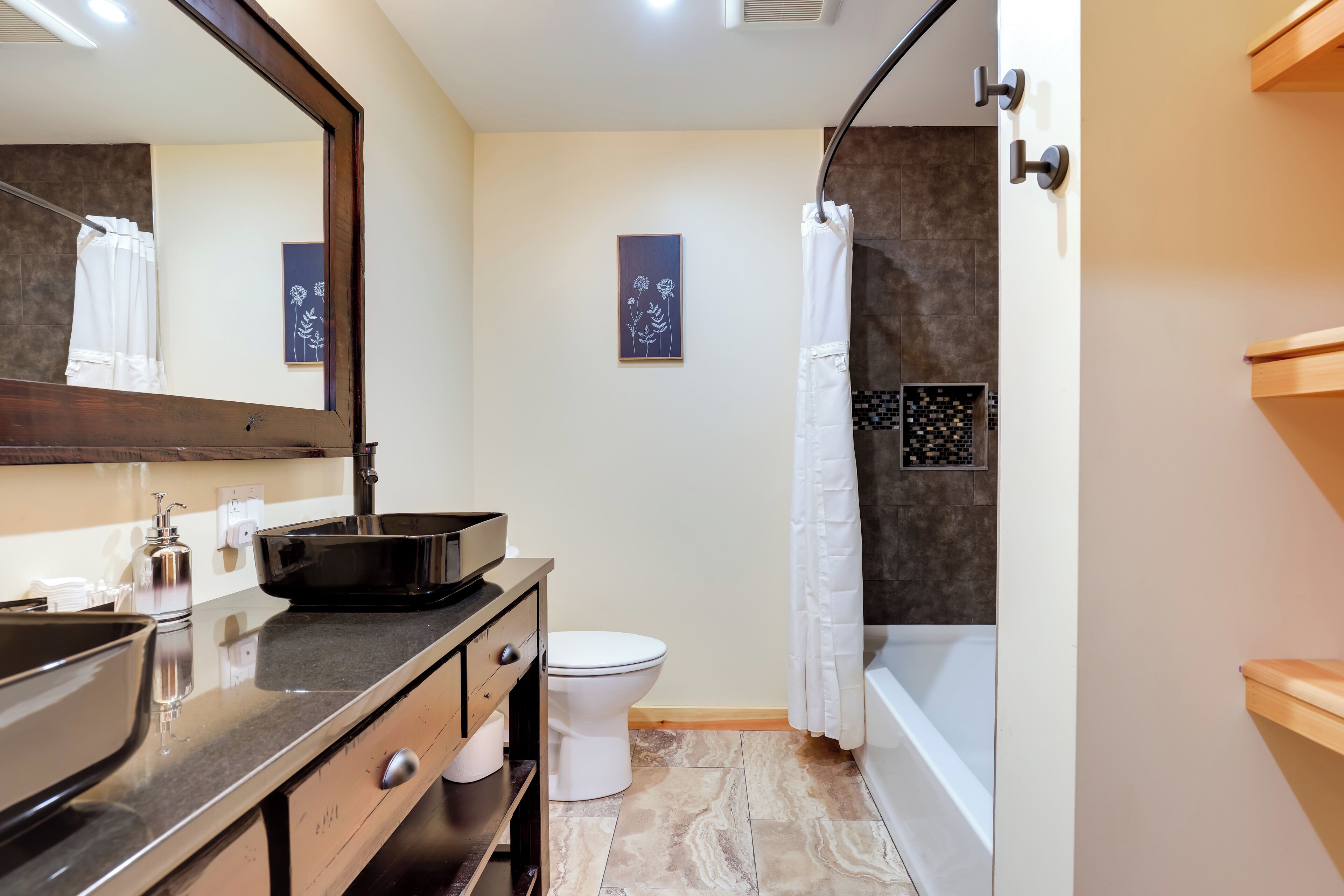 Un bany modern amb un mirall gran, un lavabo, un vàter i una banyera.