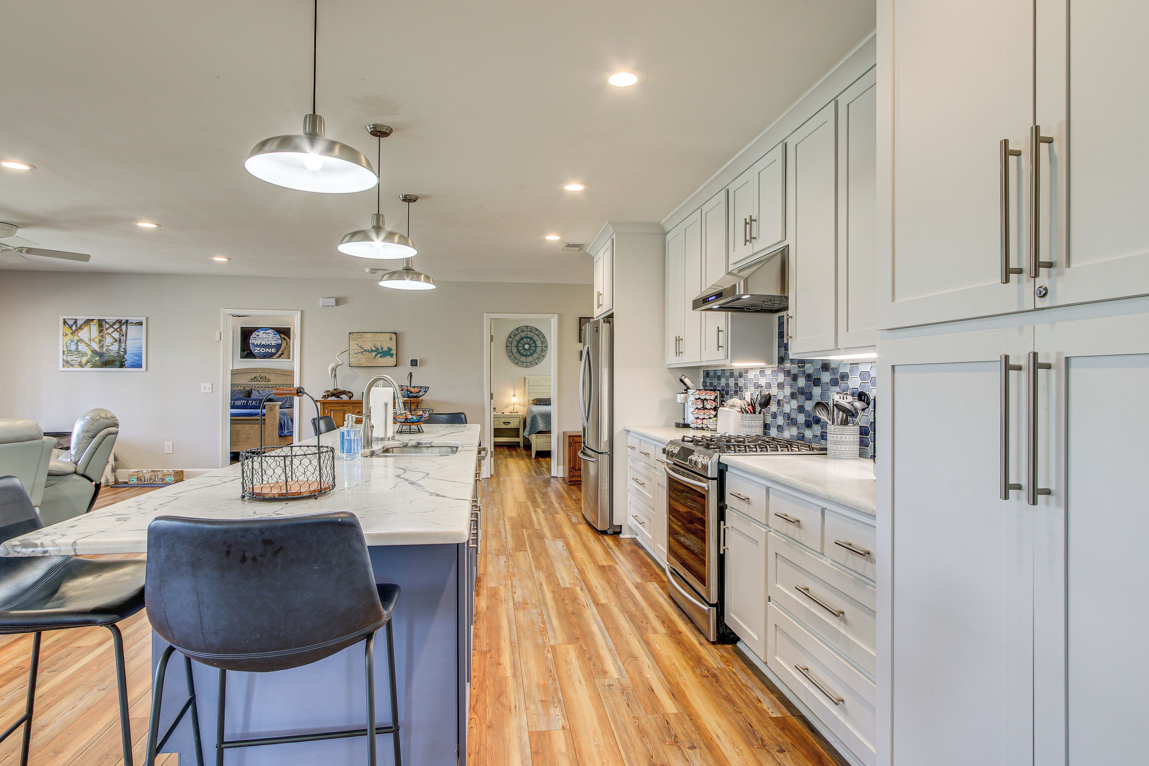 A modern kitchen with white cabinets, stainless steel appliances, and a wooden floor.