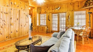 A wooden interior with a sofa, dining table, and chairs. - Private Dock + Porch: Serene Lake Greenwood Escape (Greenwood)