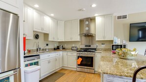 A modern kitchen with white cabinets, stainless steel appliances, a granite countertop, and a flat-screen TV mounted on the wall. - 10-acre Plot: Peaceful Getaway in Webster! (Webster)