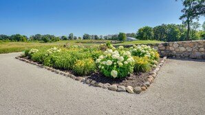 A gravel driveway leading to a stone wall with a flower bed. - 10-acre Plot: Peaceful Getaway in Webster! (Webster)