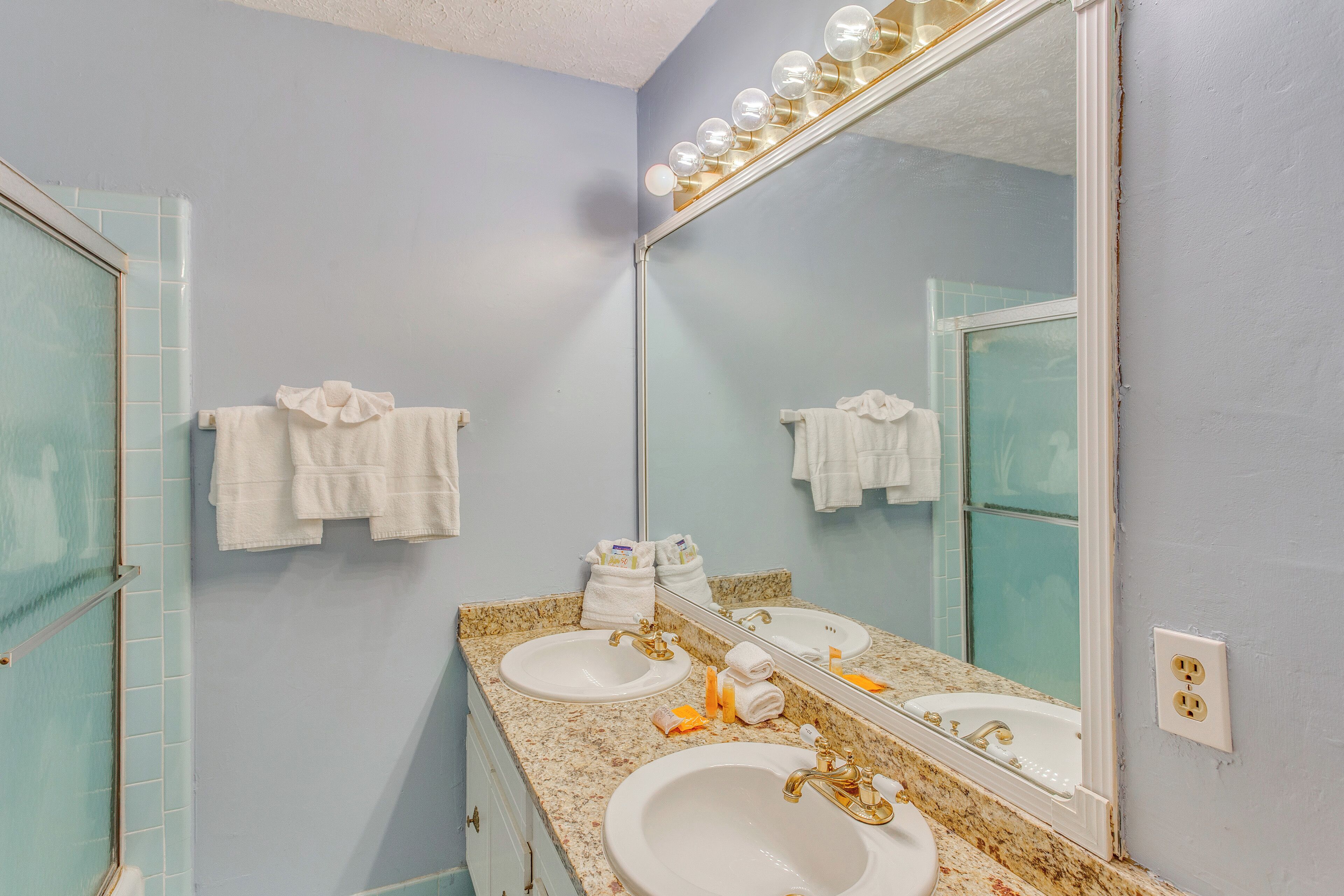 Une salle de bain avec deux lavabos, un grand miroir et un porte-serviettes.