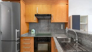 A compact kitchen with wooden cabinets, a stainless steel refrigerator, a built-in oven, and a granite countertop. - Lopimar Guillen de Castro (Canet d'en Berenguer)
