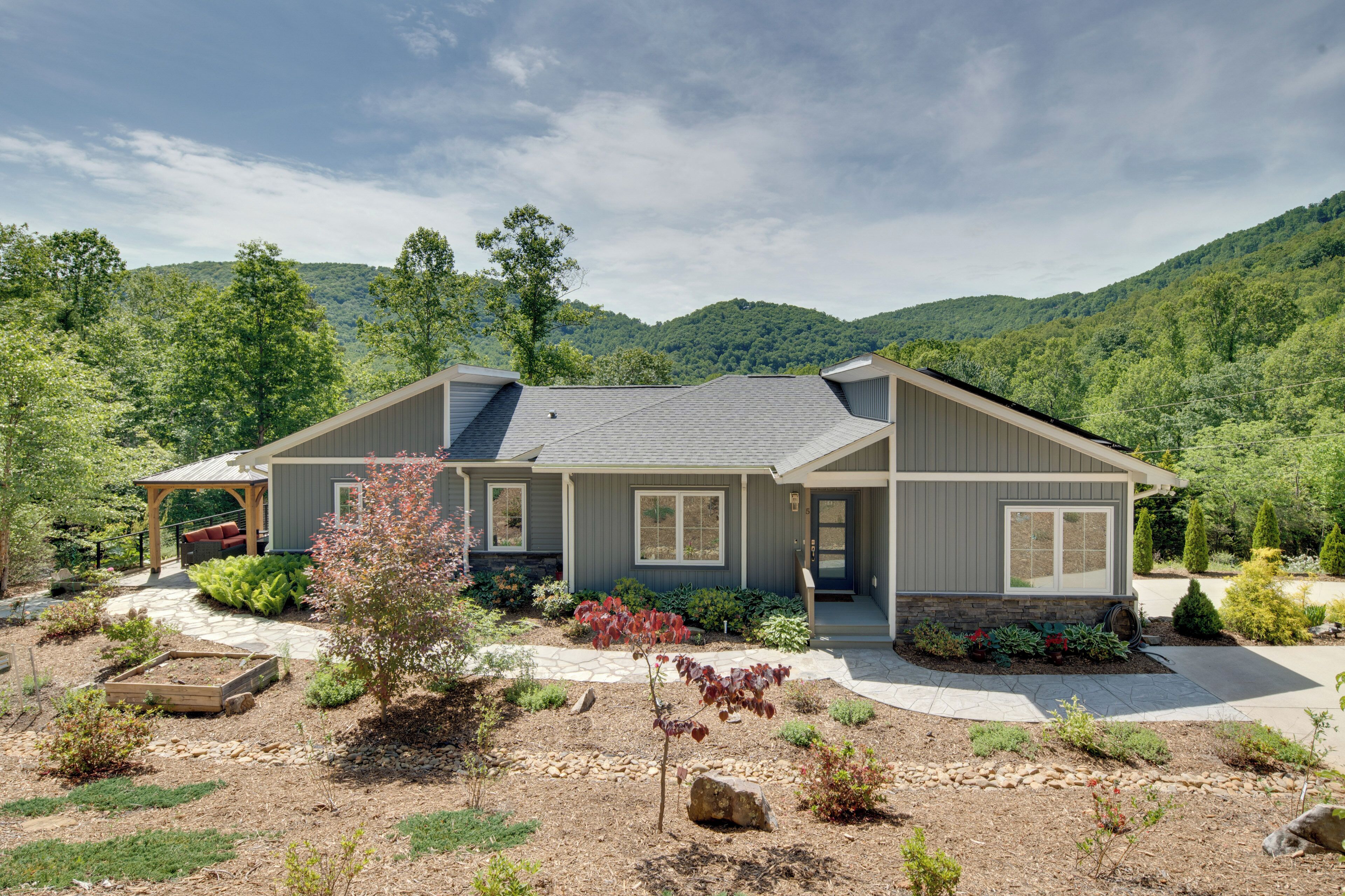 A modern house with a covered patio, a stone pathway, and a well-maintained garden.