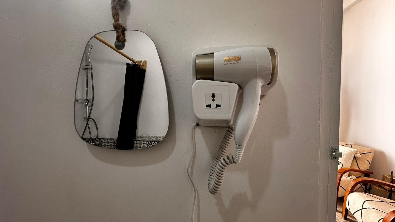 A hairdryer and a mirror mounted on a wall.