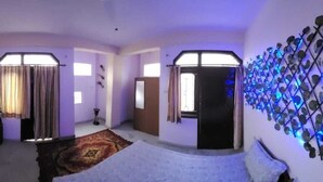 Een kamer met een bed, een raam met gordijnen, een wandlamp en een deur.