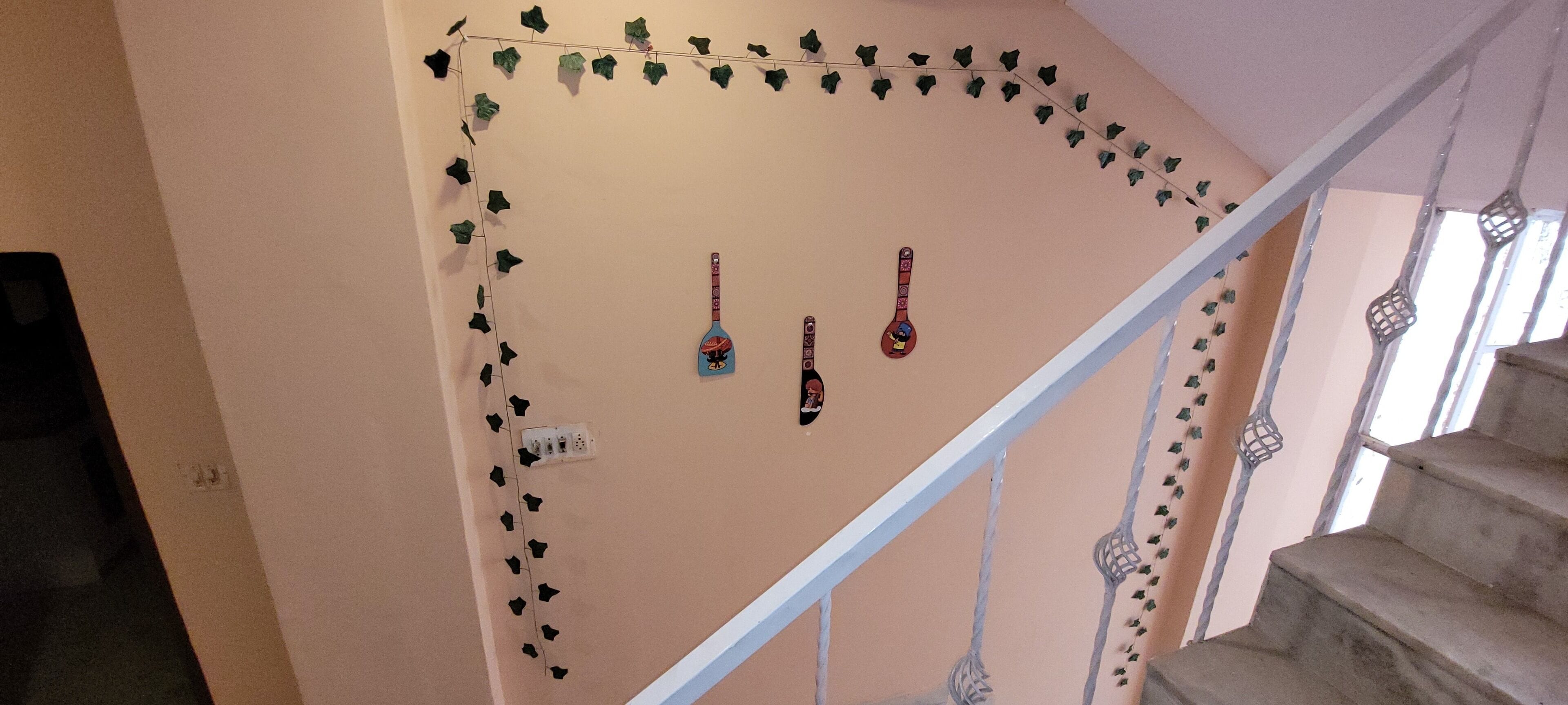 Una escalera con barandilla blanca, decorada con hiedra y dos guitarras colgadas en la pared.