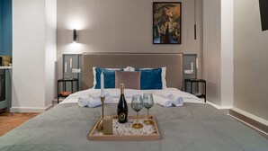 Ein ordentlich bezogenes Bett mit einem Champagner-Tablett, Gläsern und einer Flasche, begleitet von zwei Nachttischen mit Kerzen und einem Gemälde über dem Bett.