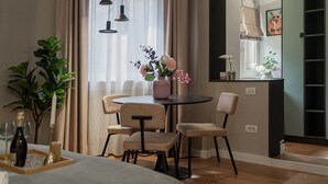 Ein modernes Hotelzimmer mit Essbereich, einer großen Kübelpflanze, einer Blumenvase und einem Bett.