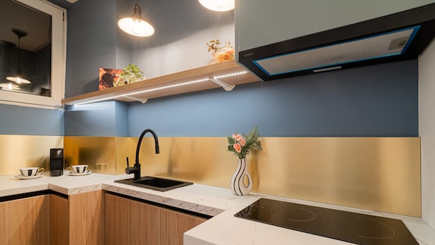 Eine moderne Küche mit einem schwarzen Spülbecken, einer weißen Arbeitsplatte und Holzschränken.