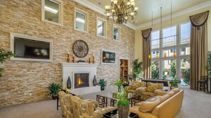A spacious living room with a stone wall, fireplace, comfortable seating, and large windows.