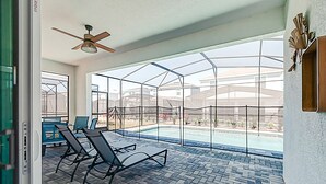 A sunroom with a glass enclosure, a ceiling fan, and a pool view. - 15976 Spacious Charming Family Getaway (Clermont)