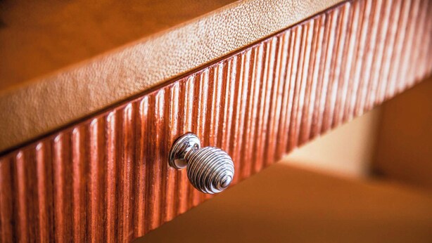 A close-up of a wooden surface with a textured pattern and a metallic knob. - Appartement Moderne - Ac-1br-4p- Geneve (Geneva)