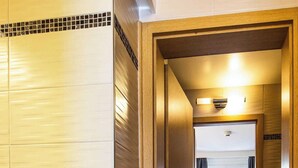Een hotelkamer met een houten deur, een klein bureau, een stoel en een bed.
