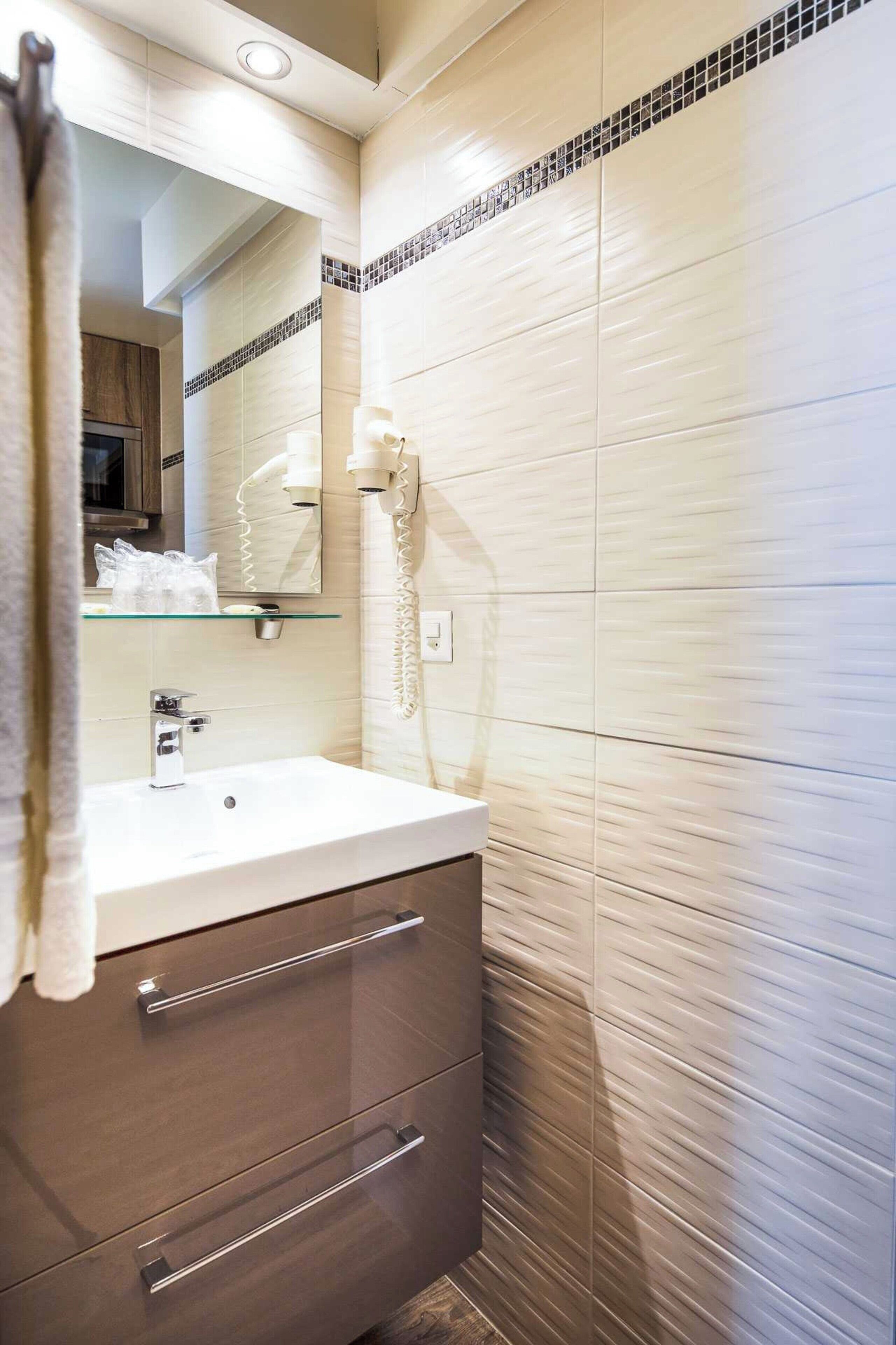 Uma casa de banho moderna com cabine de duche em vidro, lavatório branco e toucador com gavetas.