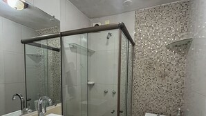 A modern bathroom with a glass-enclosed shower, a sink, and a toilet.