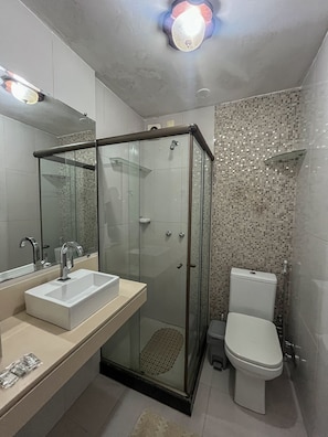 A modern bathroom with a glass-enclosed shower, a sink, and a toilet.