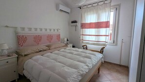 A bedroom with a bed, nightstand, lamp, and a window with curtains.