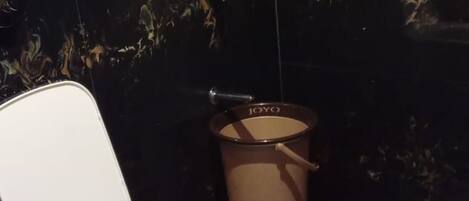 Un bagno con un water bianco, una doccia e un cestino.
