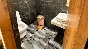 A bathroom with a toilet, bidet, and sink, marble walls, and a patterned floor.