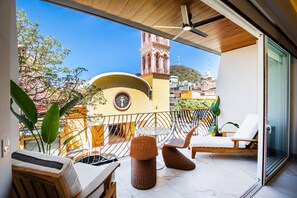 A balcony with a view of a tower, wicker furniture, and a ceiling fan.