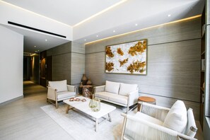 A modern living room with a sofa, armchairs, a coffee table, and a decorative wall piece.
