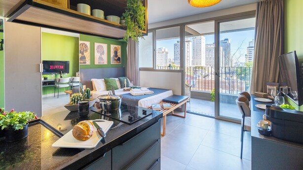 Eine moderne Wohnung mit Küche, Essbereich und einem Balkon mit Blick auf die Stadt.