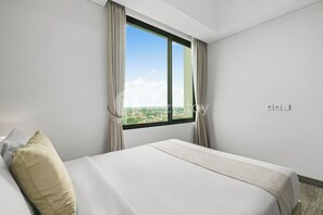 Ett hotellrum med ett stort fönster, en säng och utsikt över stadsbilden.