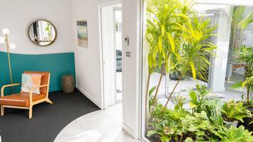 A room with a teal accent wall, a round mirror, a brown leather chair, and a small round table.