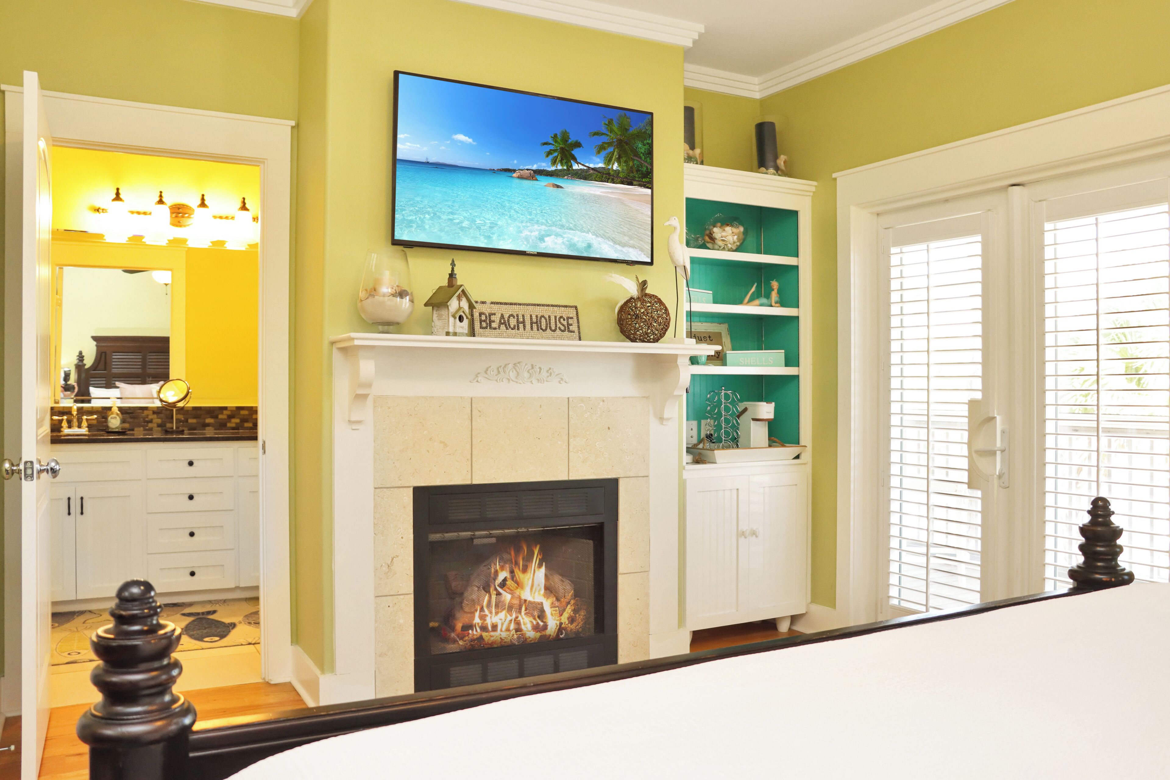 Una sala de estar con chimenea, un televisor montado encima y una estantería.