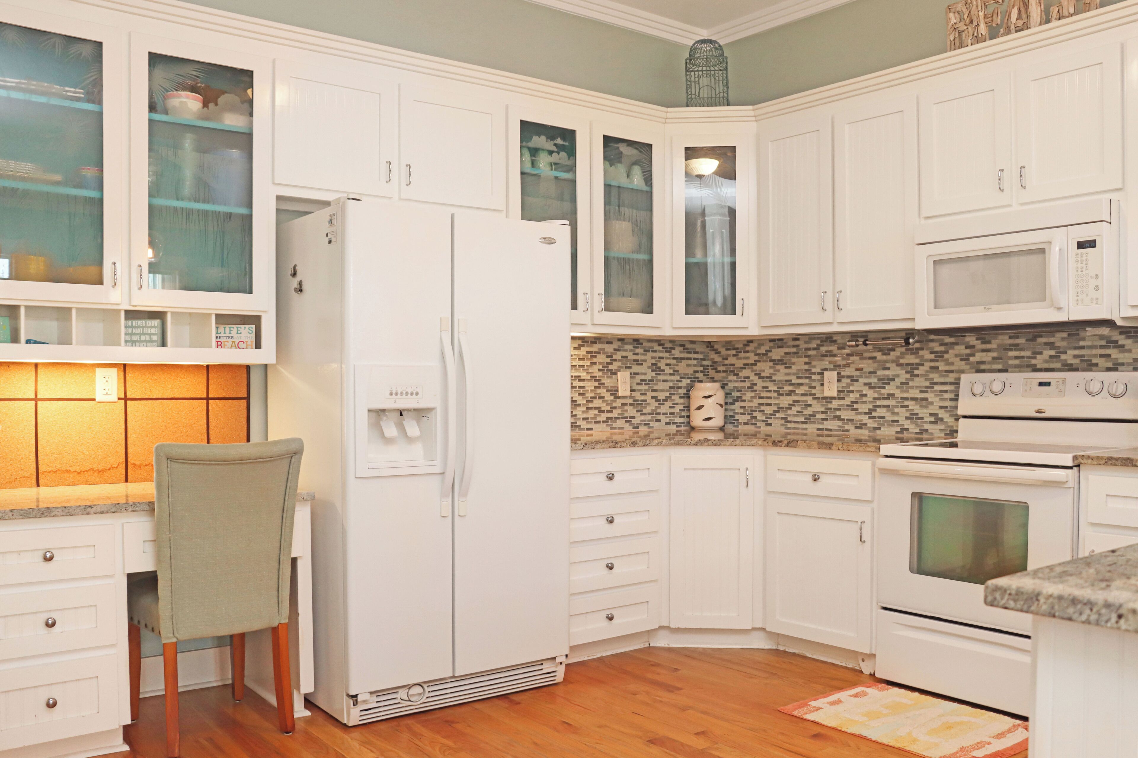 A kitchen with white cabinets, a refrigerator, a microwave, and an oven.