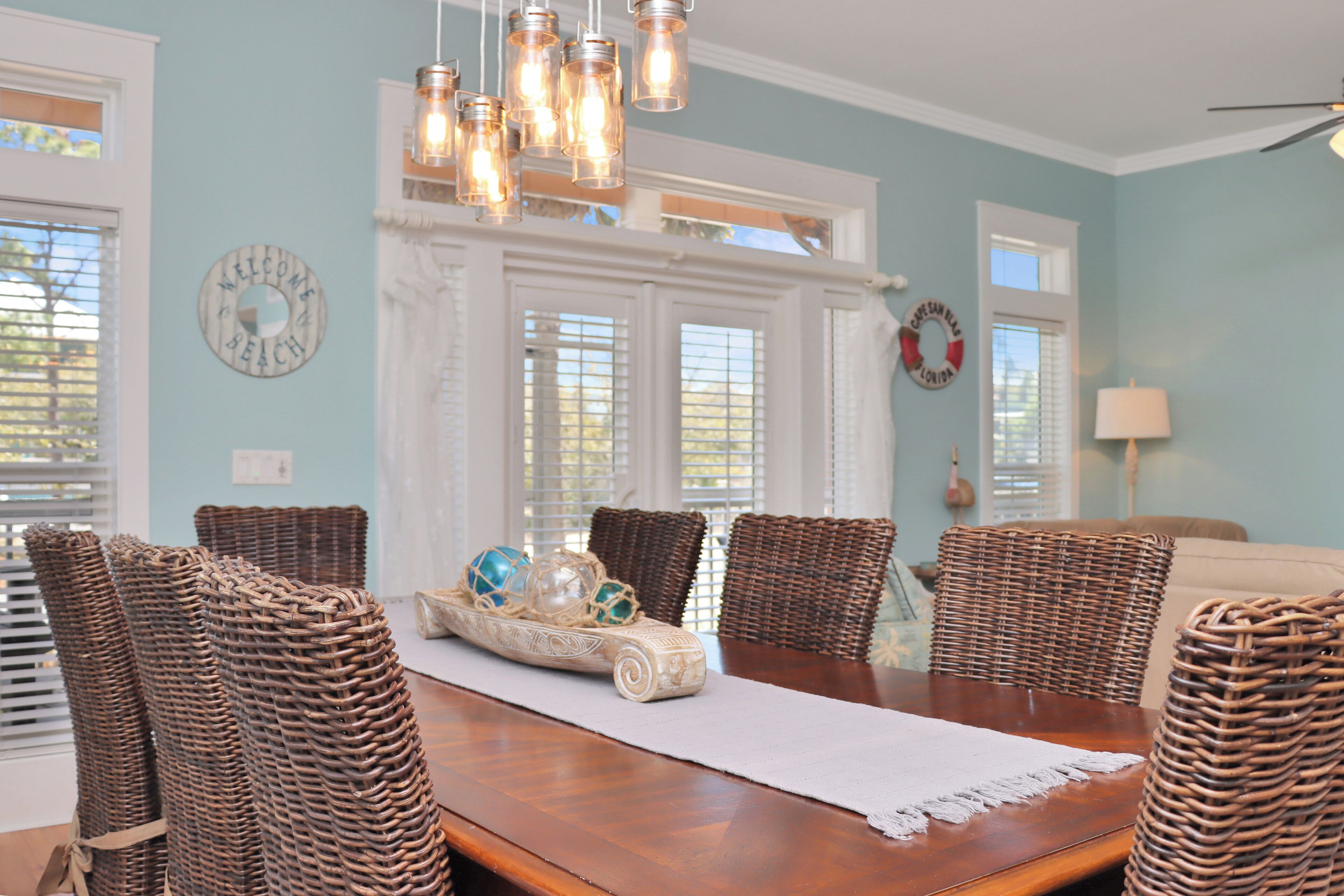 A dining area with a wooden table, wicker chairs, and a decorative centerpiece.