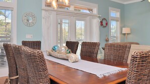 A dining area with a wooden table, wicker chairs, and a decorative centerpiece.