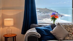Ein Zimmer mit Meerblick, einer Lampe, einer Blumenvase und einem gemusterten Kissen.