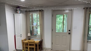 Ein Zimmer mit Esstisch, Stühlen, einem Schrank, einer Tür mit Fenster und einem gemusterten Teppich.