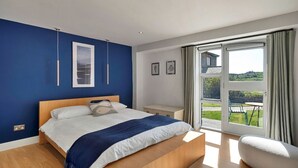 A bedroom with a large bed, a desk, and a view of the outdoors.